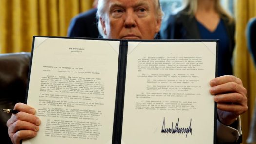 President Donald Trump holds up a signed executive order to advance construction of the Dakota Access